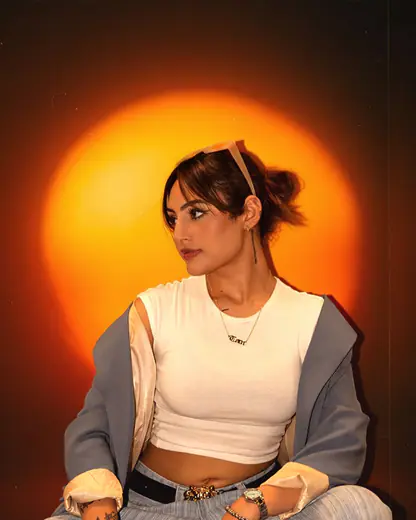 Model in a white top and denim jacket against an orange halo backdrop