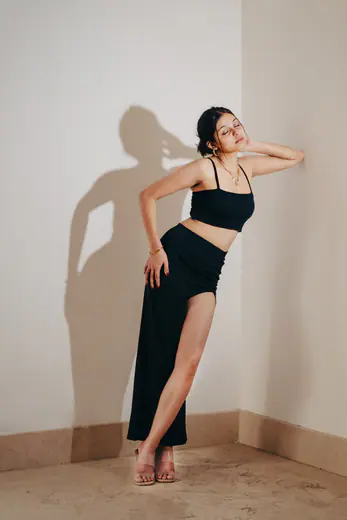 Fashion model in a black co-ord set posing against a studio wall