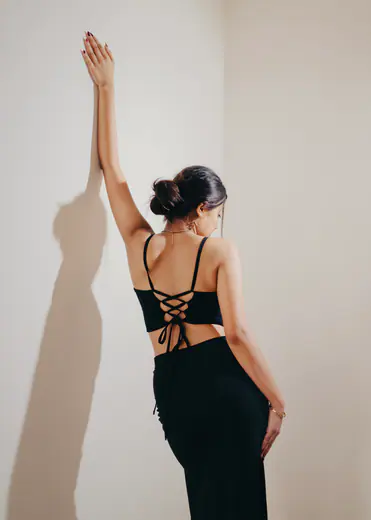 Fashion model in a black lace-up top posing with her arm raised