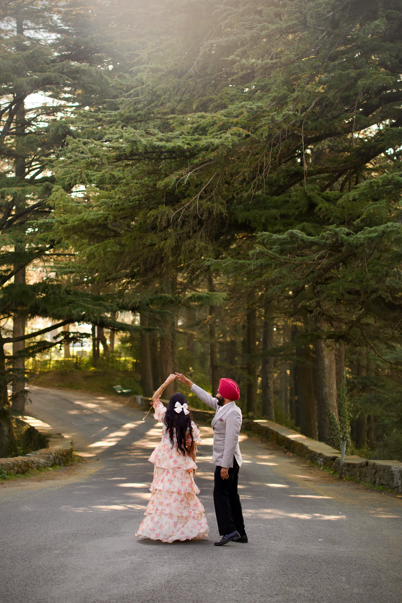 Couple dancing on a road between tall pine trees