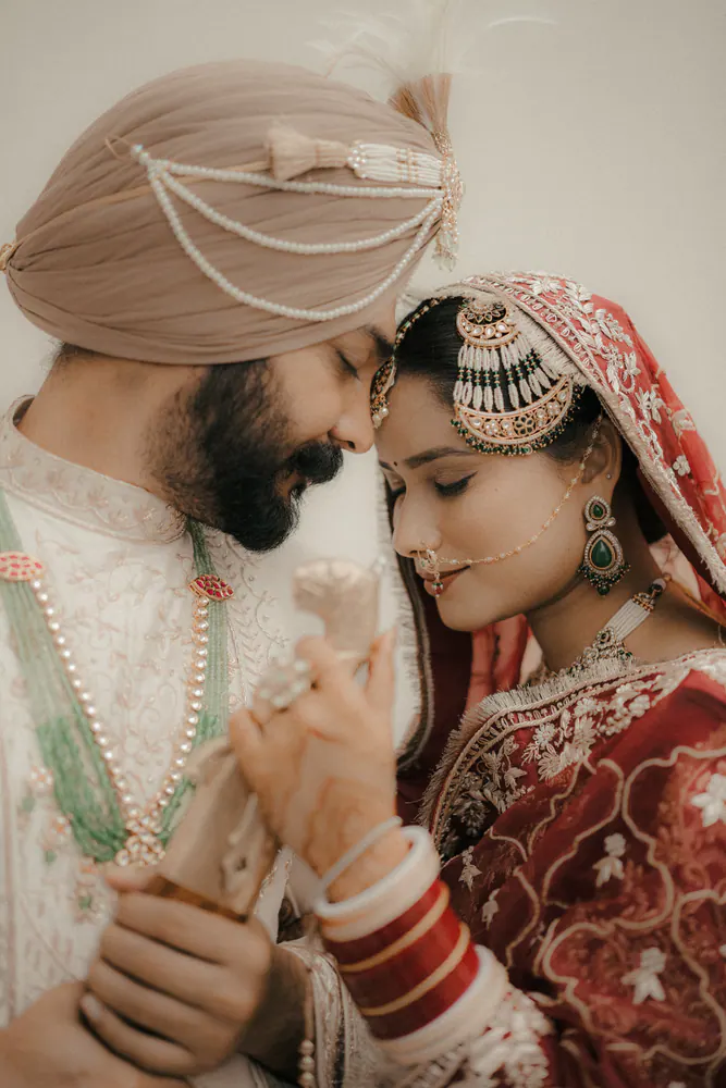 Sikh groom and bride touching foreheads in an intimate wedding portrait