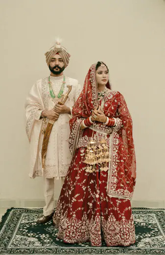 Sikh bride and groom standing together on a traditional rug